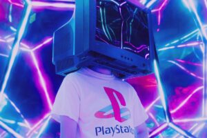 Imagem de uma menina vestindo uma camiseta branca escrito playstation e com a cabeça dentro de uma tv de tubo quatorze polegadas desligada.